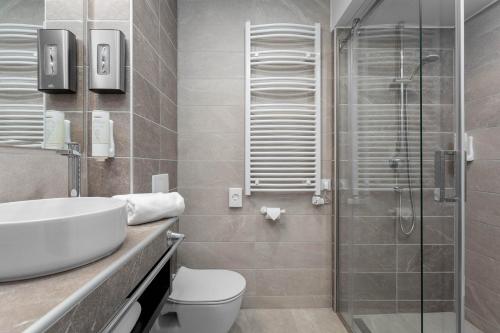 a bathroom with a toilet and a sink and a shower at Hunguest Hotel Béke in Hajdúszoboszló