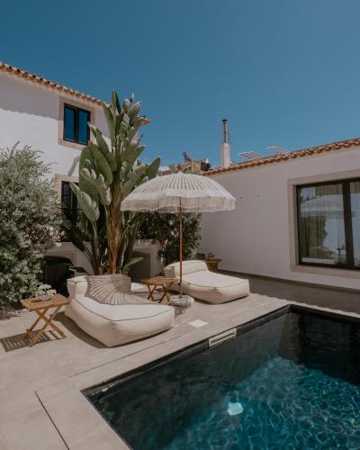a swimming pool with two lounge chairs and an umbrella at A Casa Brava in Santarém