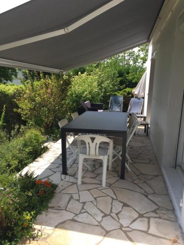 d'une terrasse avec une table et des chaises sous un auvent. dans l'établissement MAISON SAINT PALAIS /ROYAN, à Saint-Palais-sur-Mer