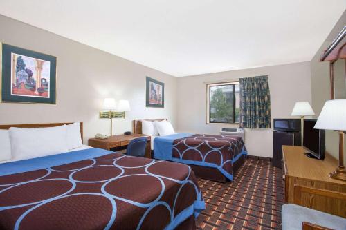 a hotel room with two beds and a television at Super 8 by Wyndham Douglas in Douglas