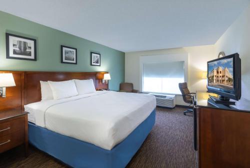 a hotel room with a bed and a flat screen tv at Days Inn by Wyndham Greenville in Greenville