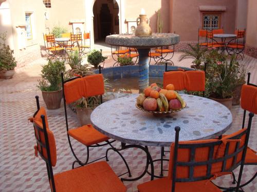 a table and chairs with a bowl of fruit on it at Kasbah Ait Kassi in Boumalne