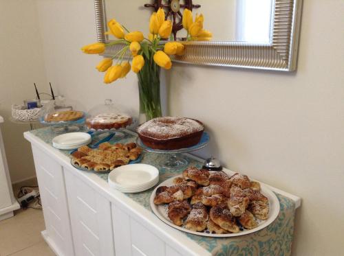 a buffet with cakes and pastries and a vase with yellow flowers at L'Approdo in San Leone