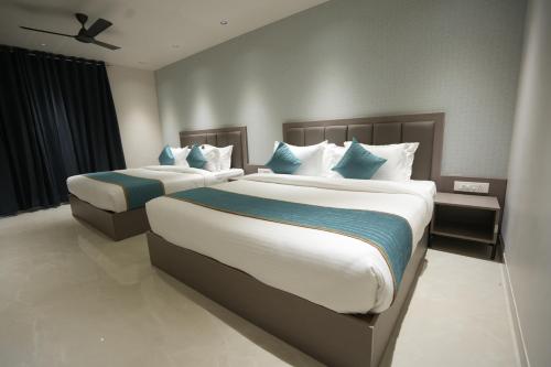 a bedroom with two beds with blue and white pillows at Hotel shree ji inn in Kishangarh