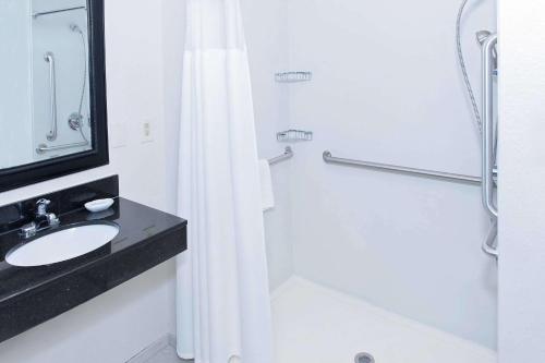 a white bathroom with a sink and a shower at AmericInn by Wyndham Hays in Hays