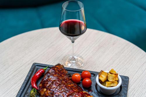 a plate of food with meat and a glass of wine at The Florian Amsterdam Schiphol Airport, WorldHotels Crafted in Hoofddorp
