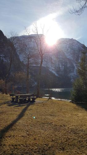 a picnic table in front of a mountain with the sun at Seeblick Krippenstein in Obertraun