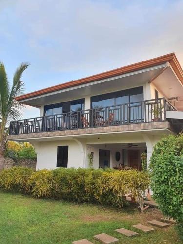 a large white house with a balcony and bushes at The Balete Resthouse in Camotes Islands