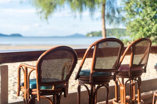 three chairs sitting on a porch near the beach at Friendship Beach Resort & Atmanjai Wellness Centre in Rawai Beach