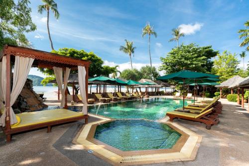 a pool at a resort with chairs and umbrellas at Friendship Beach Resort & Atmanjai Wellness Centre in Rawai Beach
