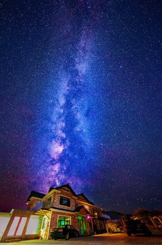 a starry night with the milky way above a house at Six-rafter Hall designer hot spring inn in Shangzhi