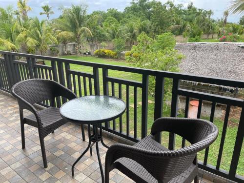 a patio with two chairs and a table on a balcony at The Balete Resthouse in Camotes Islands