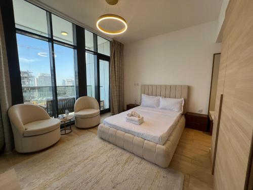 a bedroom with a bed and a chair and windows at Chic & Cozy Studio in JVC , Top Amenities & Views in Dubai