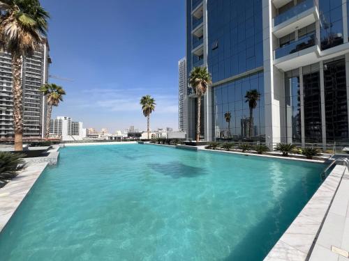 a large swimming pool with palm trees and buildings at Chic & Cozy Studio in JVC , Top Amenities & Views in Dubai