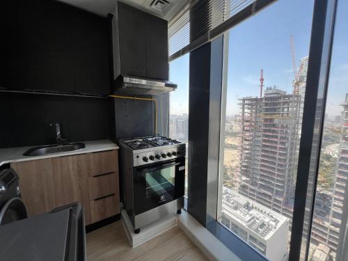 a kitchen with a stove top oven next to a window at Chic & Cozy Studio in JVC , Top Amenities & Views in Dubai