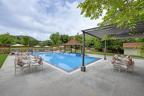 a patio with a pool and tables and chairs at The Hunting Lodge - Luxury Resort in Udaipur in Udaipur