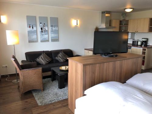 a living room with a bed and a tv and a couch at Maris Ferienwohnung Nr 46 EG mit Terrasse in Scharbeutz