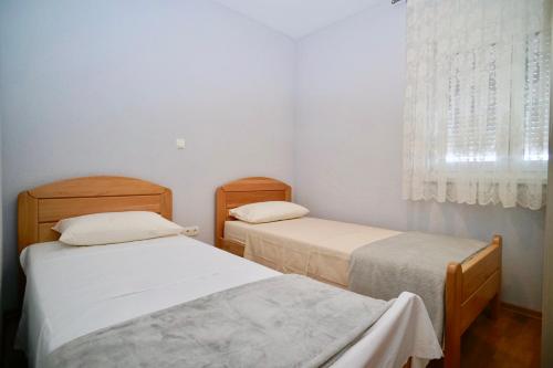 two beds in a small room with a window at La Perla Adriatica apartments Trogir-Seget in Seget Vranjica