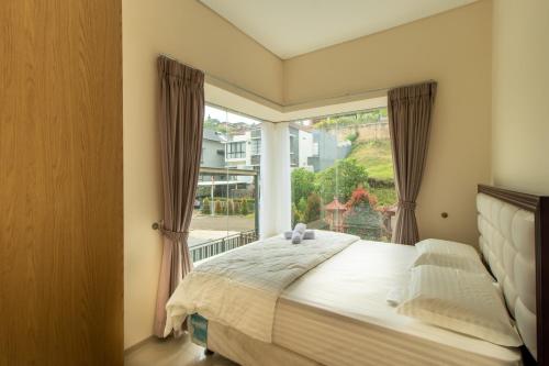 a bedroom with a bed and a large window at Family Only Spacious Hill View Villa - De Reiz Zakir Syariah 5BR in Ciburial