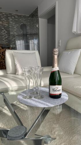 a bottle and glasses on a table in a living room at Auszeit im Heinental in Wildberg