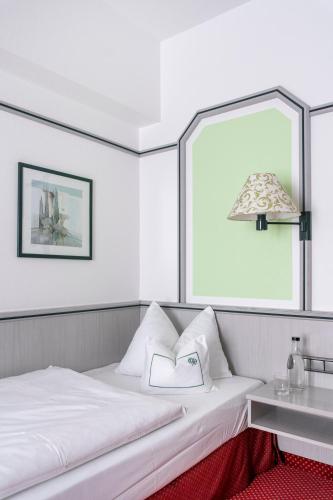 a white bed with a lamp and a table at Hotel Coellner Hof in Cologne
