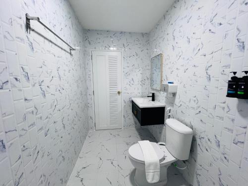 a white bathroom with a toilet and a sink at สวนปาล์มการ์เด้นโฮม เชียงคาน Suanpalm Garden Home Changkhan in Chiang Khan