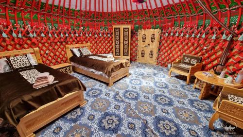 a bedroom with two beds and a table and chairs at Yurt Glamping Edelweiss Meadow at the foot of Lenin Peak in Sary-Mogul