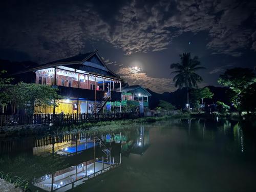 a house at night with a pond in front of it at NASRUL HOUSE HOMESTAY FOR BACKPACKERS in Maros