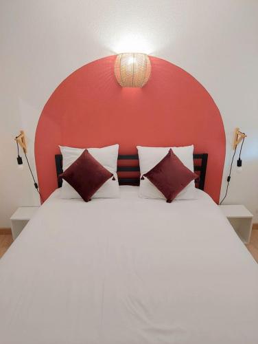 une chambre avec un grand lit avec une tête de lit rouge dans l'établissement Cosy 3 - Audincourt centre, à Audincourt