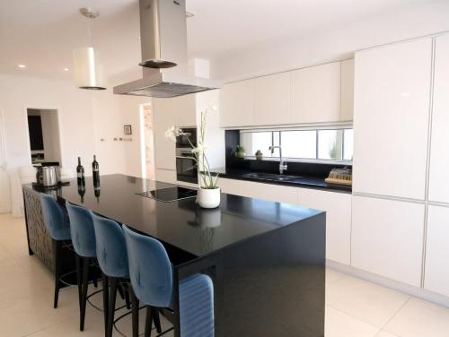 a kitchen with a black island with blue chairs at Beachfront Luxury Villa Glory in Ayia Napa