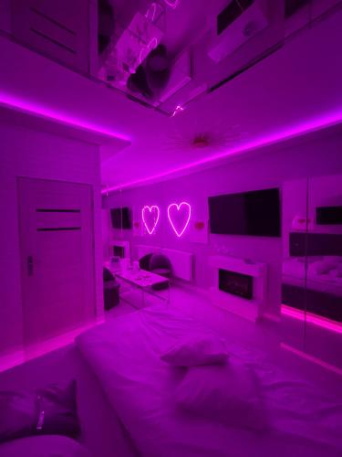 a bedroom with pink lighting and a bed with hearts on the wall at Apartament "Love Island" Jacuzzi SPA z dużą wanną z hydromasażem dla Dwojga in Gniezno