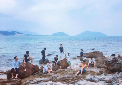a group of people sitting on rocks on the beach at Sơn Đông Hotel in Quan Lạn