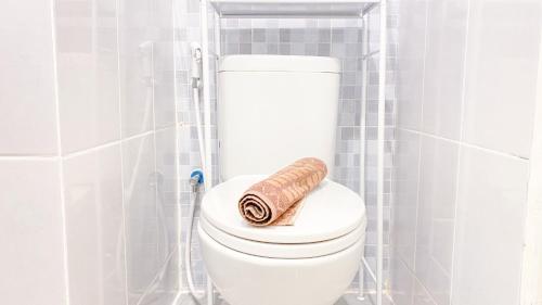 a roll of toilet paper sitting on top of a toilet in a bathroom at Simply Look and Homey Studio Tokyo Riverside PIK 2 Apartment By Travelio in Rawalembang