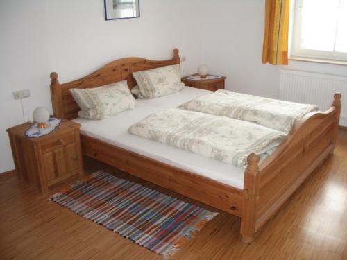 a bedroom with a wooden bed with white sheets at Ferienhof Ott im Rothenburger Land in Adelshofen