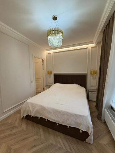a bedroom with a white bed and a chandelier at Elite Residence Exclusive View in Chişinău