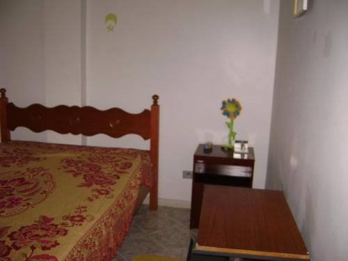 1 dormitorio con cama y mesa de madera en Apartamento Temporada Enseada, en Guarujá