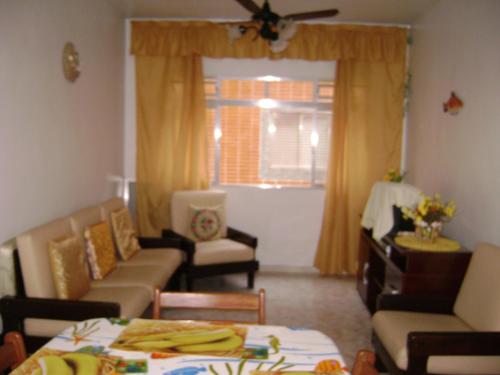 a living room with a couch and chairs and a table at Apartamento Temporada Enseada in Guarujá