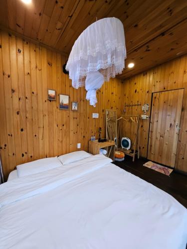 a bedroom with a large white bed with wooden walls at Nhà Bắp in Da Lat