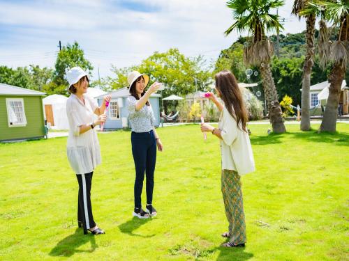 three women standing in a yard playing with bubbles at Takatakiko Glamping Resort in Tsurumai