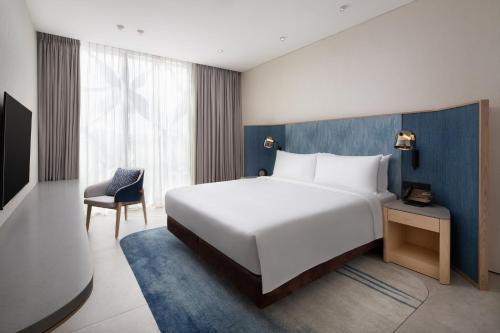 a bedroom with a large white bed and a chair at Crowne Plaza Changi Airport by IHG in Singapore