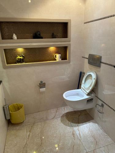 a bathroom with a toilet and a yellow trash can at super nova 1 in Lahore