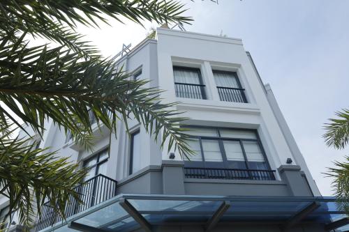 a white building with palm trees in front of it at Lá Riverside Boutique Hotel in Mỹ Phước