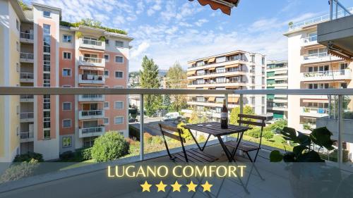 a balcony with a table and a view of buildings at Casa Luce with Private Gym and Netflix - Lugano in Viganello