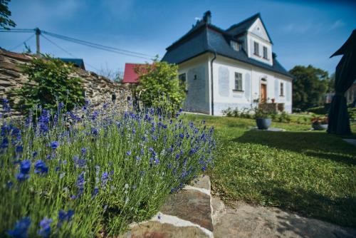 a white house with purple flowers in the yard at Barokní kaplanka 1796 A. D. - luxusní apartmány v Českém ráji in Železný Brod