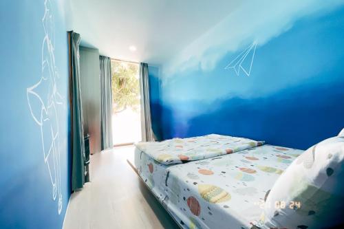 a bedroom with a bed with a blue wall at Little Ryukyu Hermit Crab Homestay in Xiaoliuqiu