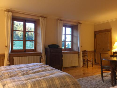 a bedroom with a bed and a table and windows at L'Annexe Apparthôtel du Haut-Doubs, 4 étoiles in Les Hôpitaux-Vieux