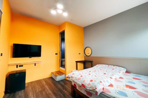 a bedroom with a bed and a flat screen tv at Little Ryukyu Hermit Crab Homestay in Xiaoliuqiu