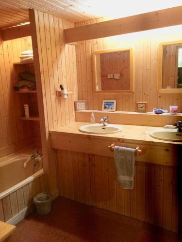 a bathroom with two sinks and a tub and a mirror at L'Annexe Apparthôtel du Haut-Doubs, 4 étoiles in Les Hôpitaux-Vieux