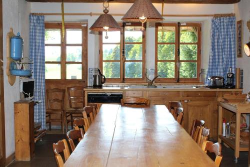 una gran cocina con una larga mesa de madera y sillas en L'Annexe Apparthôtel du Haut-Doubs, 4 étoiles, en Les Hôpitaux-Vieux