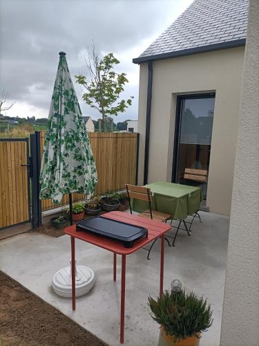 un patio avec une table et un parasol vert dans l'établissement Proche GR34 , Studio 